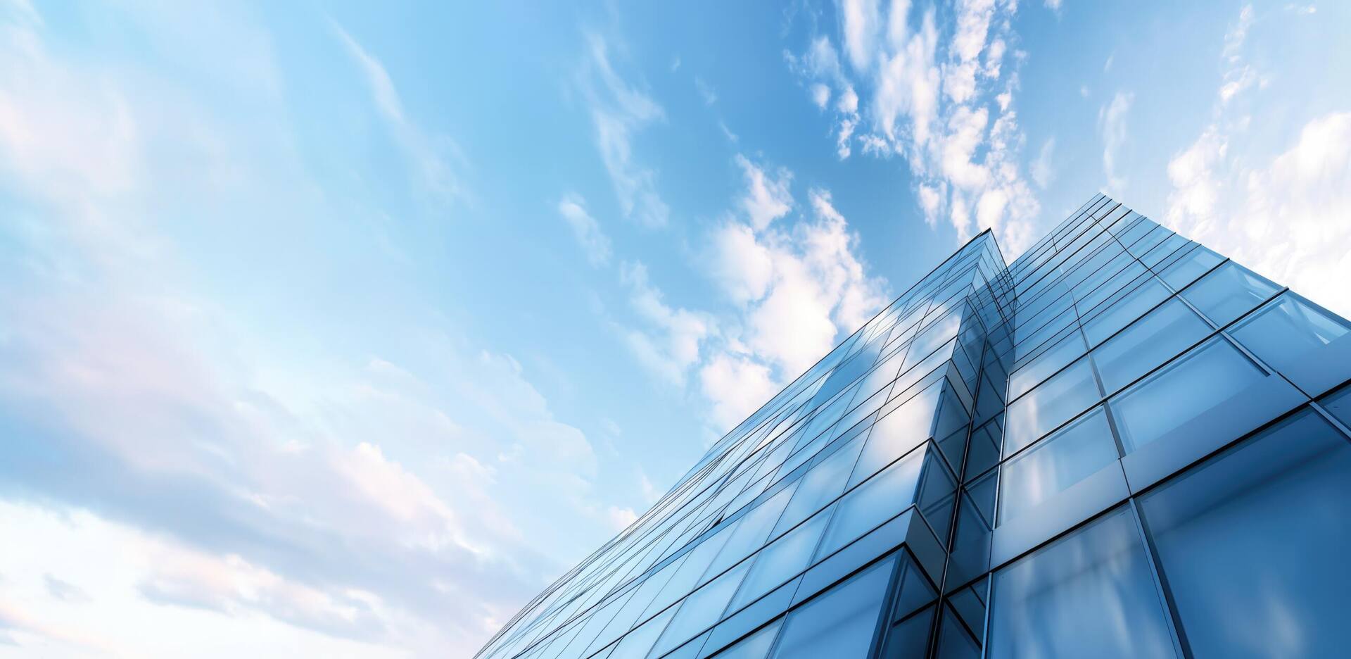 Glass corporate tower rising into a bright sky